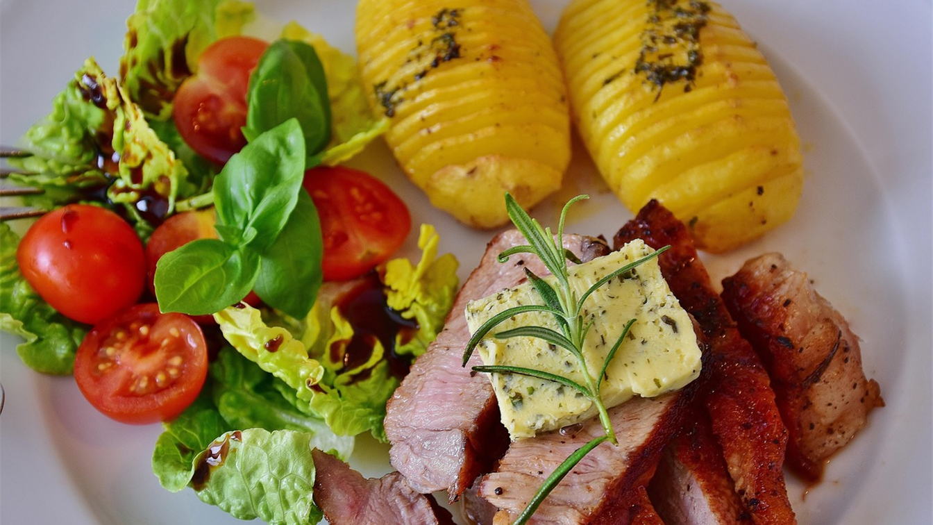 Batata hasselback assada ao lado de carne grelhada e salada