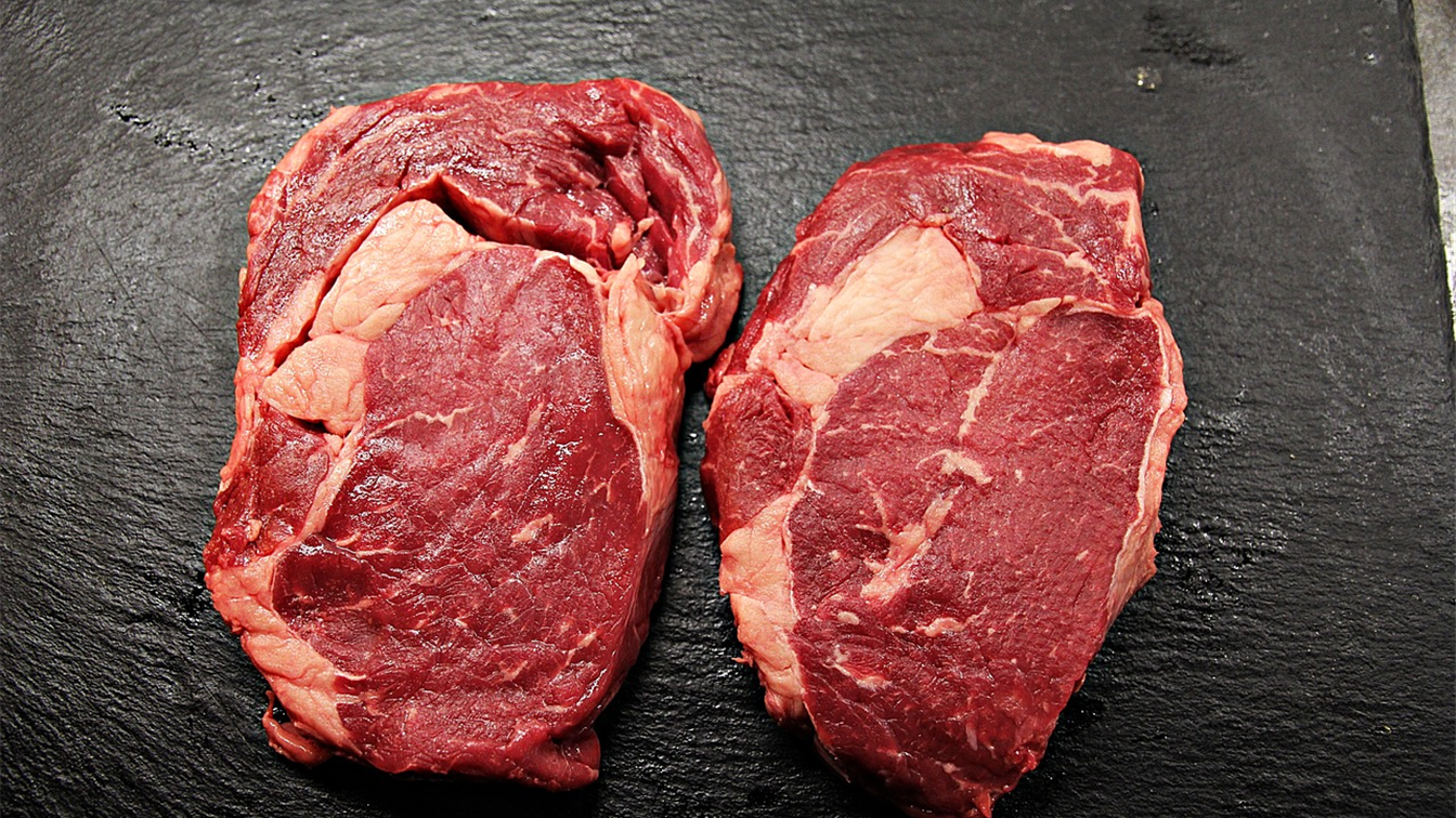 Dois bifes de carne bovina crua sobre pedra escura