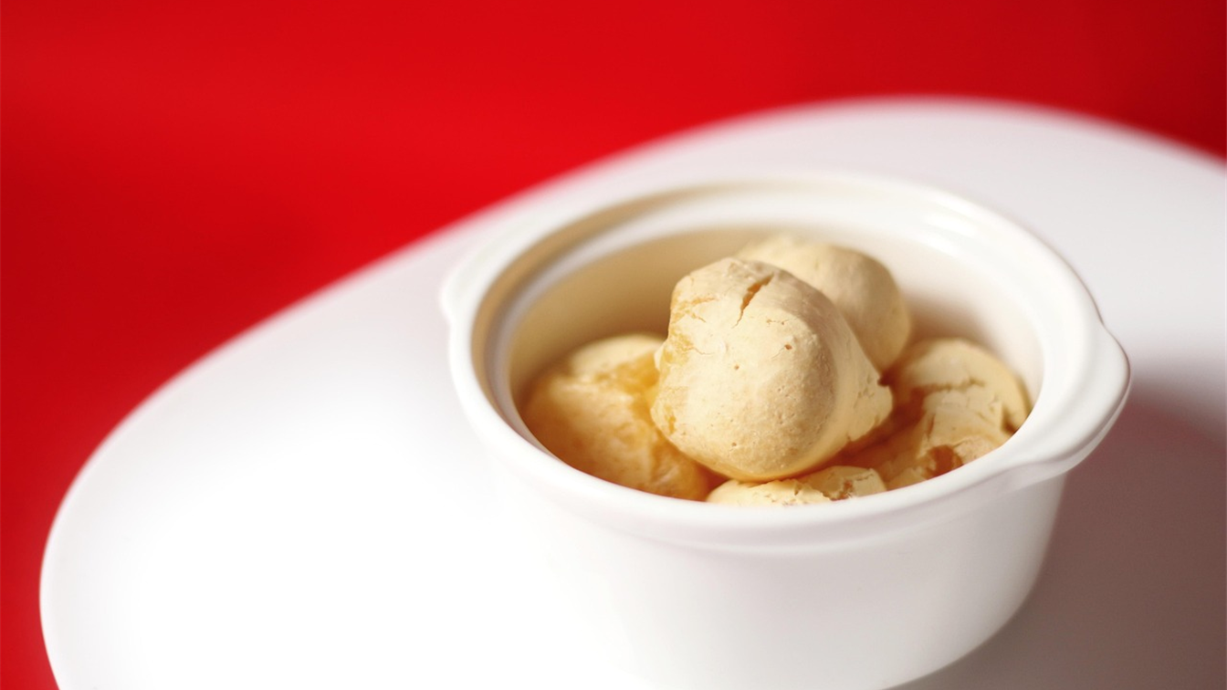 Bolinhas de pao de queijo douradas em uma tigela branca